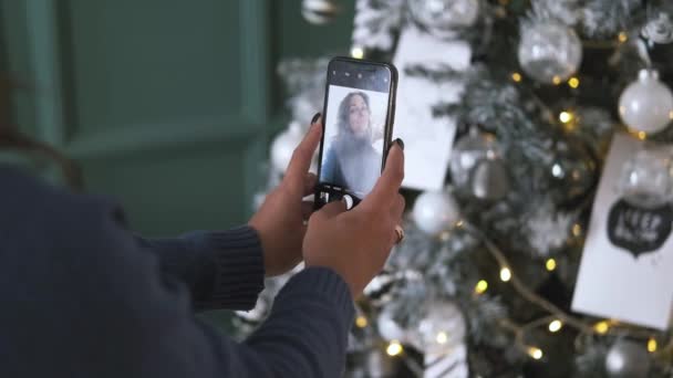 Close up of attractive brunette taking selfie on cellphone over christmas tree background — Stock Footage Close up of attractive brunette taking selfie on cellphone over christmas tree background Video Clip