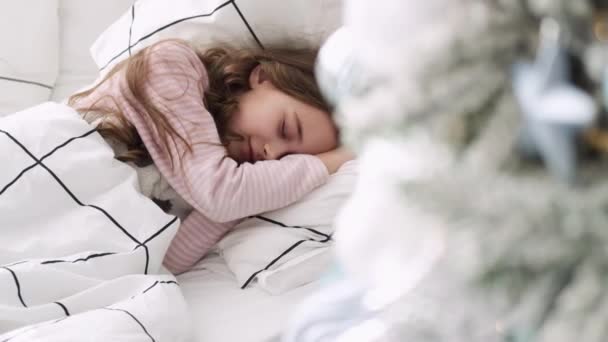 Little girl sleeps on the background of the Christmas tree. girl sleeping on bed at christmas — Stock Footage Little girl sleeps on the background of the Christmas tree. girl sleeping on bed at christmas Royalty Free Stock Video