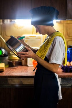 Mutfakta üniformalı genç bir kadın yemek pişiriyor.