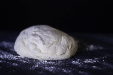 Koyu arka planda beyaz ve turuncu ışıklı ev yapımı pizza hamuru..