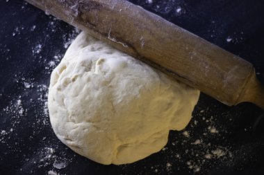 Koyu arka planda beyaz ve turuncu ışıklı ev yapımı pizza hamuru..