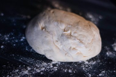 Koyu arka planda beyaz ve turuncu ışıklı ev yapımı pizza hamuru..