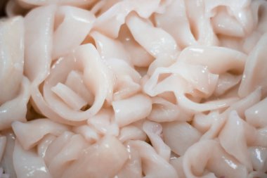 Lavaboda su ve eldivenle mürekkep balığını temizleyen biri. Bu mürekkep balığı yemek pişirmek için kullanılacak. Mürekkep balığı halkaları metal bir kapta olacak..