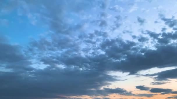 Vidéo sur un ciel nuageux bleu au coucher du soleil avec des lumières orange et rose 