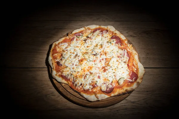 Пицца с огурцами салями в темноте — стоковое фото