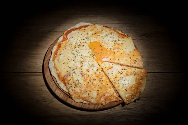 Пицца с желтком, нарезанный кусок, в темноте — стоковое фото