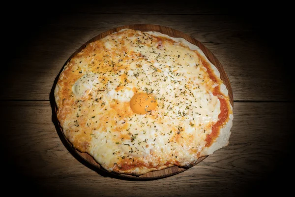 Пицца с яичным желтком в темноте — стоковое фото