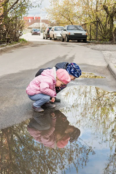 İki çocuk su birikintisinde bakıyor. — Stok fotoğraf