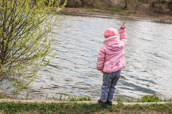 Child throws a stick into the water — Stock Photo, Image