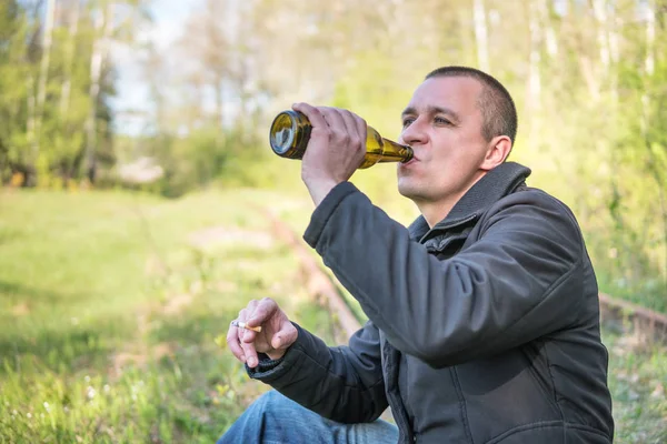 Man sitter på rälsen dricka öl — Stockfoto