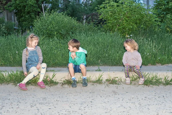 Дети сидят на бордюре и играют. — стоковое фото