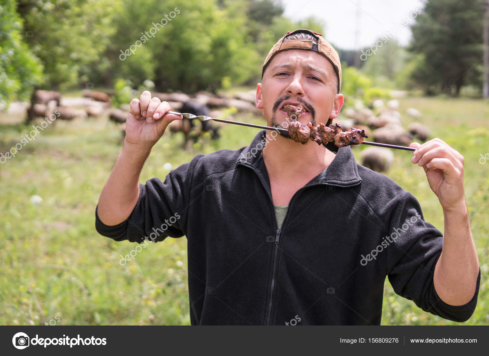 жарим шашлык. пикник шашлык на природе. парень с шашлыком. шашлык на шампуре. шампур в руке.