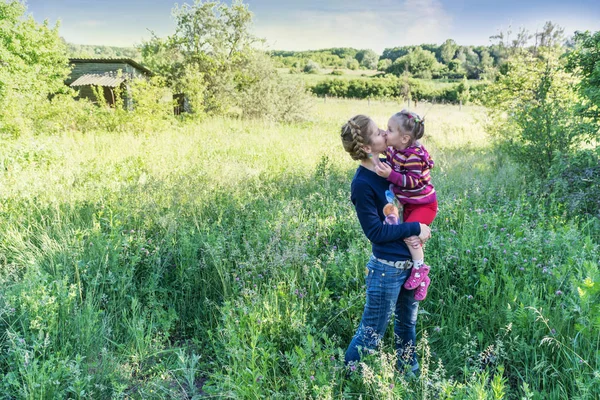 Mother kisses daughter in nature — Stock Photo, Image