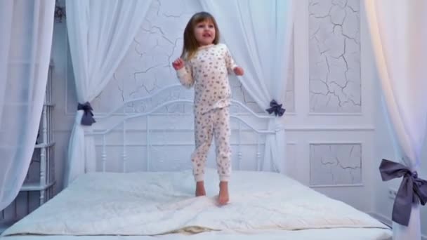 Mädchen springt auf das Bett — Stockvideo