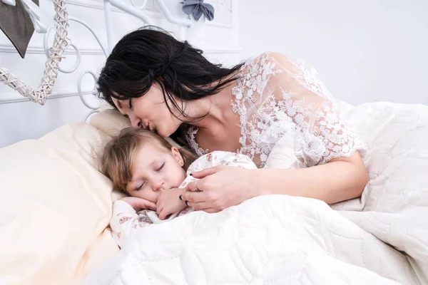 Мама целует спящую дочь — стоковое фото