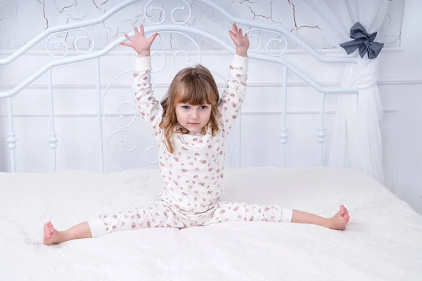 Niño está haciendo ejercicios en la cama — Foto de Stock