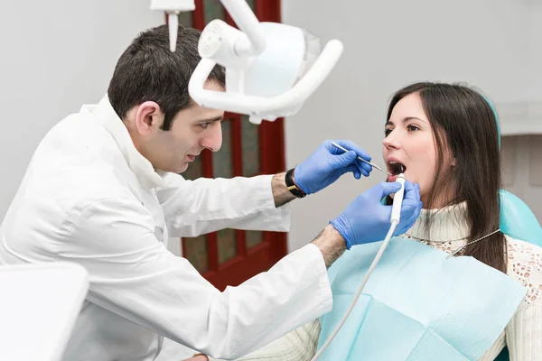 El dentista limpia los dientes del paciente con ultrasonido — Foto de Stock