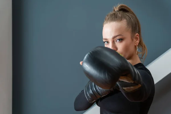 portrait of a beautiful athletic woman in boxing gloves in a protective pose