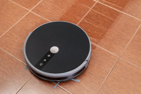 Siyah süpürge kahverengi bir fayansın zeminini yıkıyor.