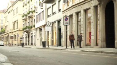 Maskeli yaşlı bir adam, kameranın önünden geçerken el sallıyor.