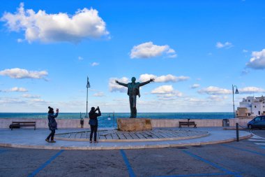 Polignano A Mare, İtalya - 12 Şubat 2019. Domenico Modugno 'nun bronz heykeli Arjantinli heykeltıraş Hermann Mejer tarafından İtalya' nın güneyindeki Puglia Bölgesi Polignano a Mare 'de inşa edildi..