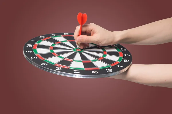 hand holding  target dart board and  pointing on top score target on isolated gradient red background, Business target concept.