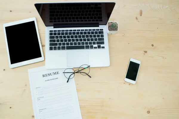 Office table with Laptop, tablet, smartphone and resume informat — Stock Photo, Image