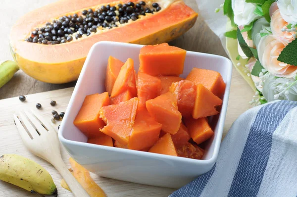 Mesa de cocina con rodajas de fruta fresca de papaya en placa de madera. c) — Foto de Stock