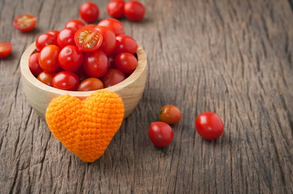 Kitchen table with dwarf tomatoes on wood plate with orange hear — Stock Photo, Image