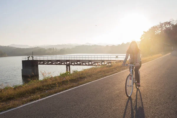 young woman ride bicycle on load dam in morning, concept of Asia