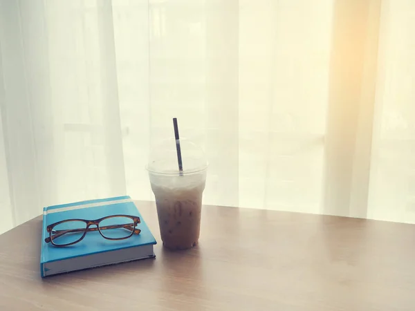 Mesa de oficina con taza de café de hielo y gafas modernas en libro a —  Fotos de Stock