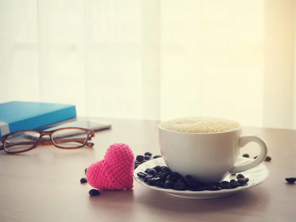 Mesa de escritório de madeira com xícara de café latte e forma de coração rosa — Fotografia de Stock