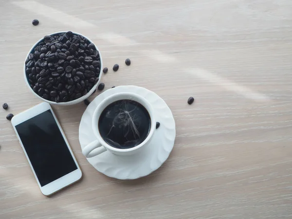 Дерев'яний стіл з гарячою чорною кавою, кавовим зерном і порожнім екраном — стокове фото
