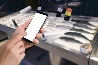 insan eli tutun ve cellphone ile bulanık deniz ürünleri raf market arka plan boş ekran dokunmatik.