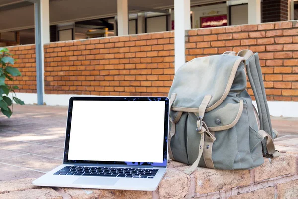 blank screen laptop and Green Travel Bag at park. view from front notebook screen, concept of technology with travel.