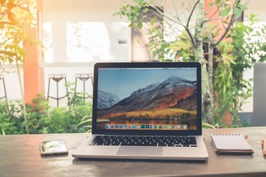 Chonburi, Tayland - Kasım 12,2017: Ofis masaları ile Macbook Pro retina macos yüksek Sierra ekran, Apple iphone6, boş ekran defter kağıt üzerinde Bahçe ağaç ile 13 inç.