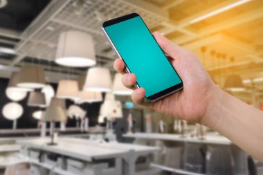 insan eli tutun akıllı telefon, tablet, cep telefonu ile boş perde lamba raf Mağaza dekorasyon ev online alışveriş kavramı.