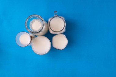 Mavi arkaplanda kopyalama alanı olan grup süt şişesi.