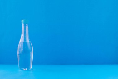 Mavi arka planda bir şişe su, ön masadan görüş..