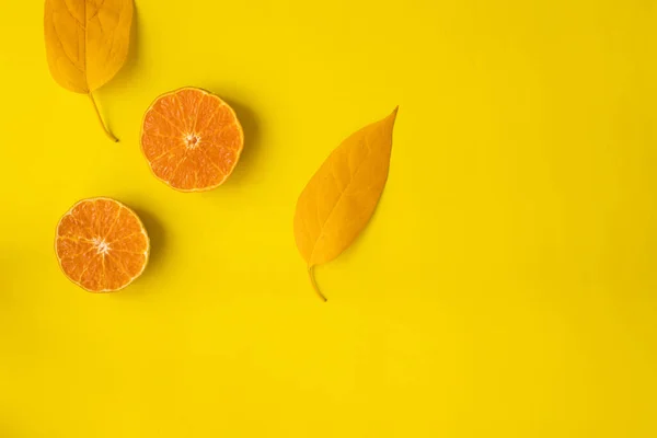 Sliced orange fruit and yellow fruit on yellow background with copy space.