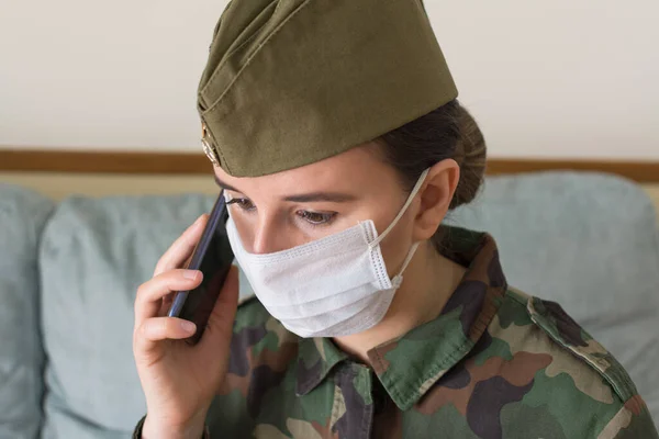 Portrait of a female army officer in uniform and surgical mask. Talking to the cell phone. Fighting the virus. Pandemic coronavirus. Portrait army series.Series of army portraits.