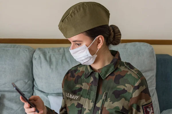 Portrait of a female army officer in uniform and surgical mask. Looking at the cell phone. Fighting the virus. Pandemic coronavirus. Portrait army series.Series of army portraits.