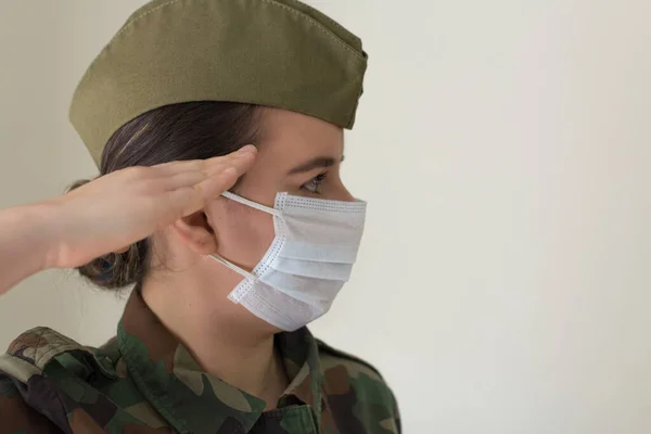 Portrait of a female army officer in uniform and surgical mask. Doing a military salute. Fighting the virus. Pandemic coronavirus. Portrait army series.Series of army portraits.