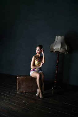 Parlak takım elbiseli bir jimnastikçi kahverengi bir bavul ve eski bir lamba üzerinde