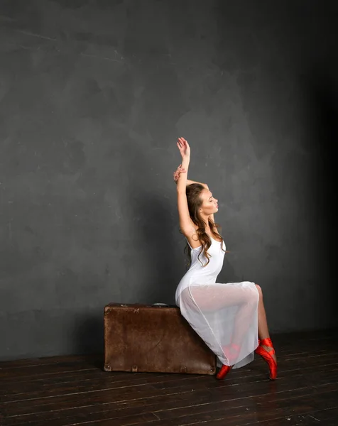 Bailarina Vestido Branco Pointes Vermelho Senta Uma Mala Fundo Cinza — Fotografia de Stock