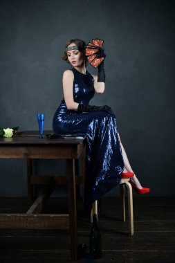 Mavi gece elbisesi içinde, siyah eldivenli, falcı kartlı güzel bir kadın.