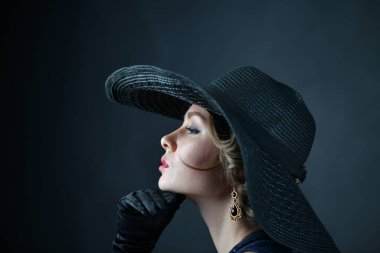 Siyah eldivenli ve siyah şapkalı mavi gece elbisesi giyen güzel bir kadın.