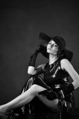 Siyah eldivenli, siyah şapkalı ve silahlı, mavi gece elbisesi giyen güzel bir kadın.