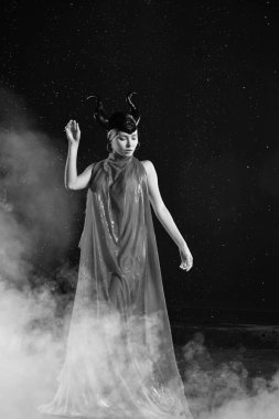 Toprak Tanrıçası 'nın kırmızı elbisesi içindeki güzel kadın dumanın içinde yağmurda dans ediyor.