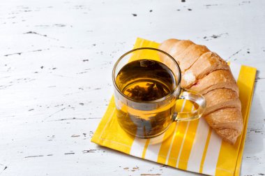 Taze pişmiş kruvasanlar peçete üzerinde çay ile.